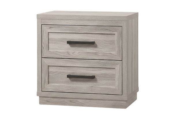 Una mesita de noche de dos gavetas con acabado en madera de color gris claro y tiradores de barra de metal oscuro, mostrada sobre un fondo blanco liso.