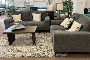 Sofá y loveseat gris con cojines en un ambiente de sala de estar.