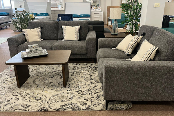 Sofá y loveseat gris con cojines en un ambiente de sala de estar.