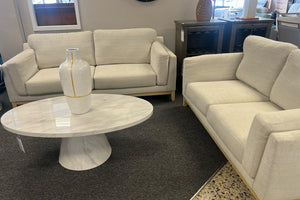 Loveseat y sofás beige y una mesa de mármol en una habitación.