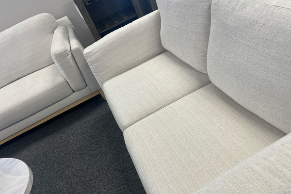 Sofá modular de color beige en una habitación con alfombra gris oscuro.