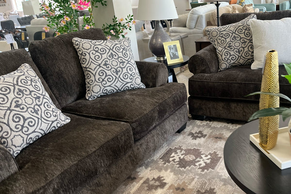 Sofá y loveseat modular marrón con cojines estampados en una sala de exposición.
