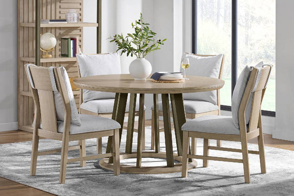 Comedor con una mesa redonda de madera y cuatro sillas a juego con cojines grises.