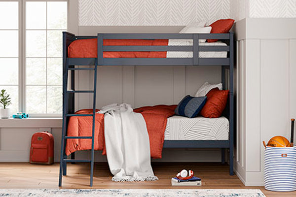 Litera con ropa de cama roja y blanca en una habitación con ventana y alfombra.